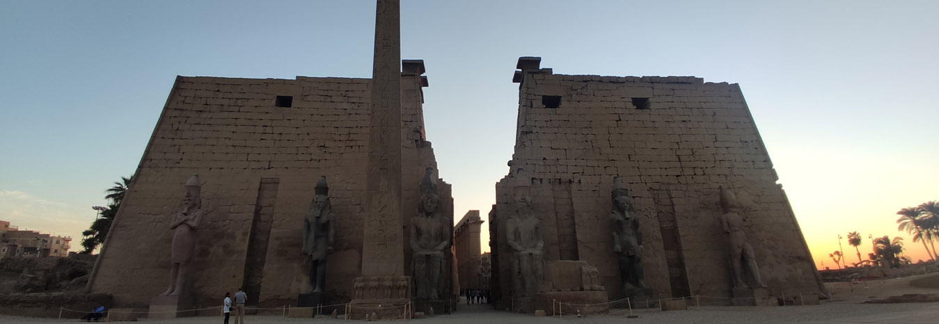The illuminated columns and pylon of Luxor Temple at night under a blue sky