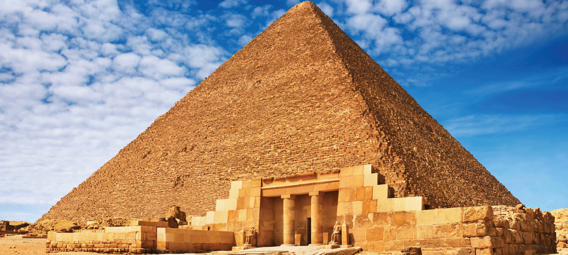The Great Pyramid of Giza under a blue sky with white clouds, representing Egypt luxury tours and Nile cruise packages by Avatar Travel.