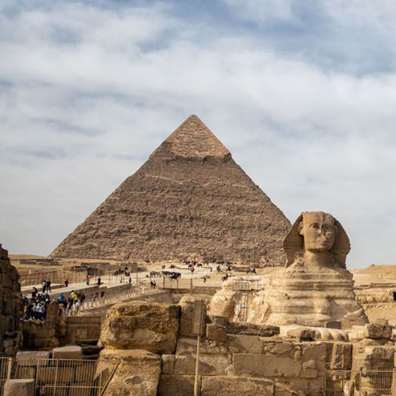 The Great Sphinx of Giza with the Great Pyramid in the background under a blue sky, featured in the 13 Days Classical Egypt Tour by Avatar Travel.