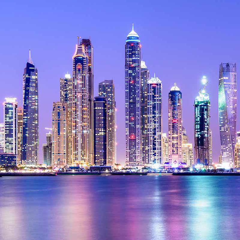 Illuminated skyscrapers of Dubai Marina at night reflected on the water, part of the 6 Days Dubai Experience Tour by Avatar Travel.