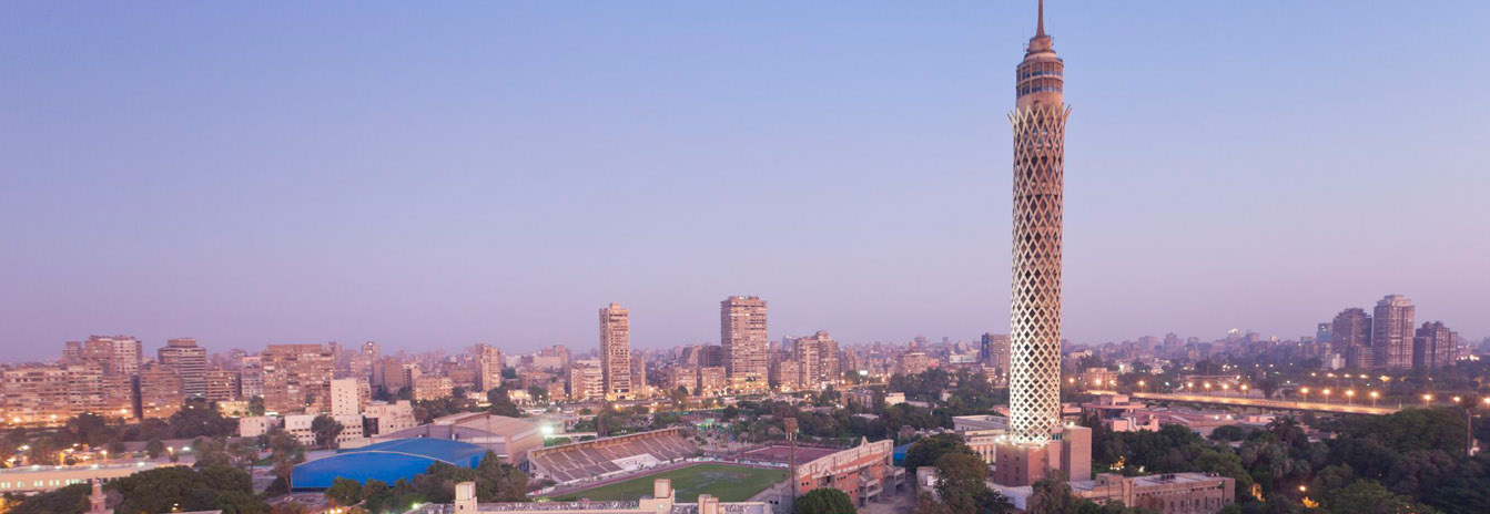 Panoramic view of Cairo Tower and the Nile River at sunset, showcasing the vibrant city skyline.
