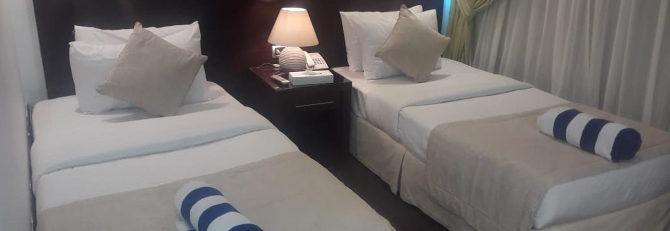 A luxury guest cabin on the Dahbya Merit featuring twin beds, large panoramic windows, and oriental rugs.