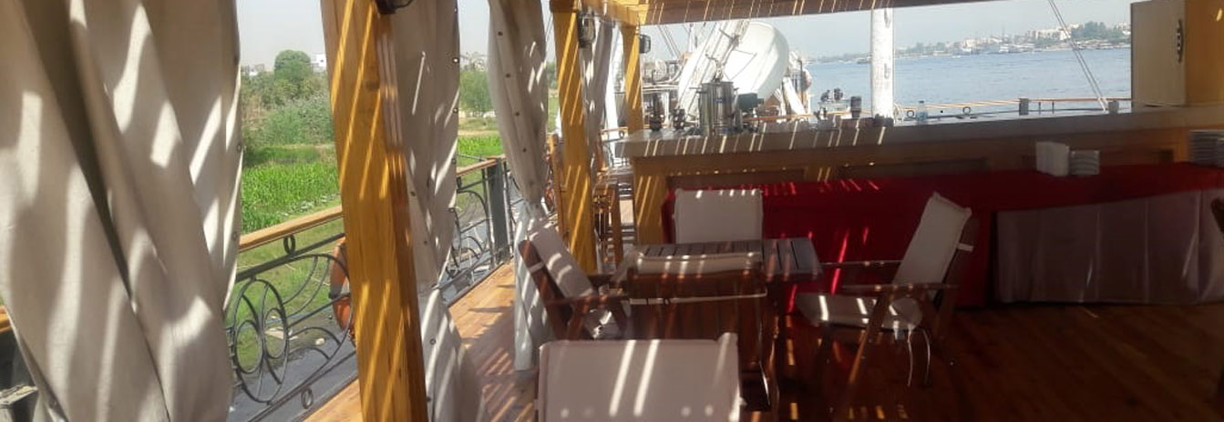 A beautifully set dining table on the wooden sun deck of the Dahbya Merit under a canvas canopy.