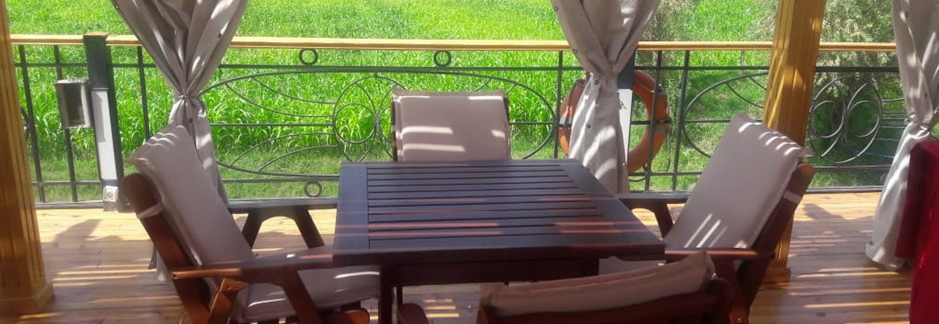 An outdoor dining setup on the wooden deck of the Dahbya Merit under a shaded canopy.