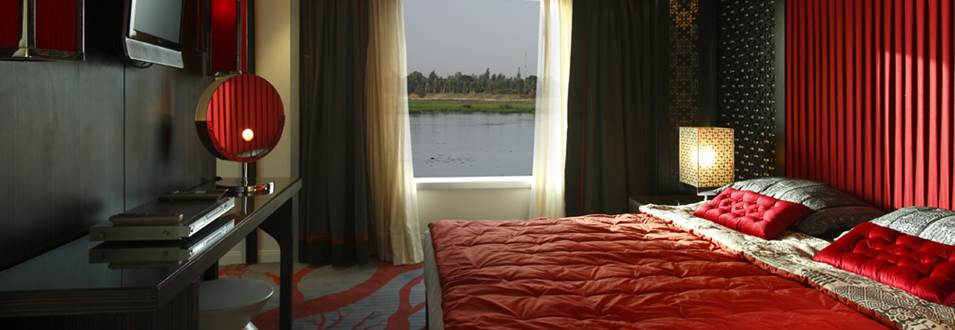 A luxury cabin on the MS Darakum with a large window, plush bedding, and warm decor.