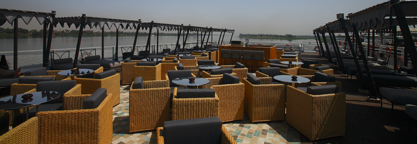 The large sun deck of the MS Darakum with a swimming pool, shaded cabanas, and panoramic views of the Nile riverbank.