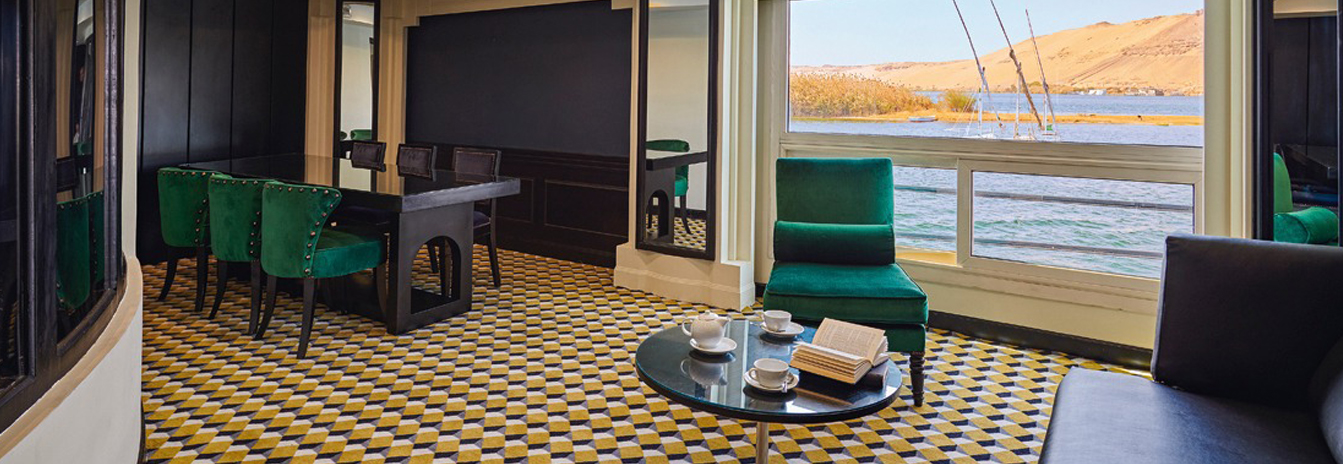 A refined guest cabin on the MS Hamees with a large window overlooking the Nile riverbank.