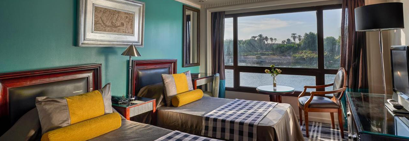 A spacious luxury suite on the Mövenpick MS Sunray with large windows and contemporary Swiss decor.