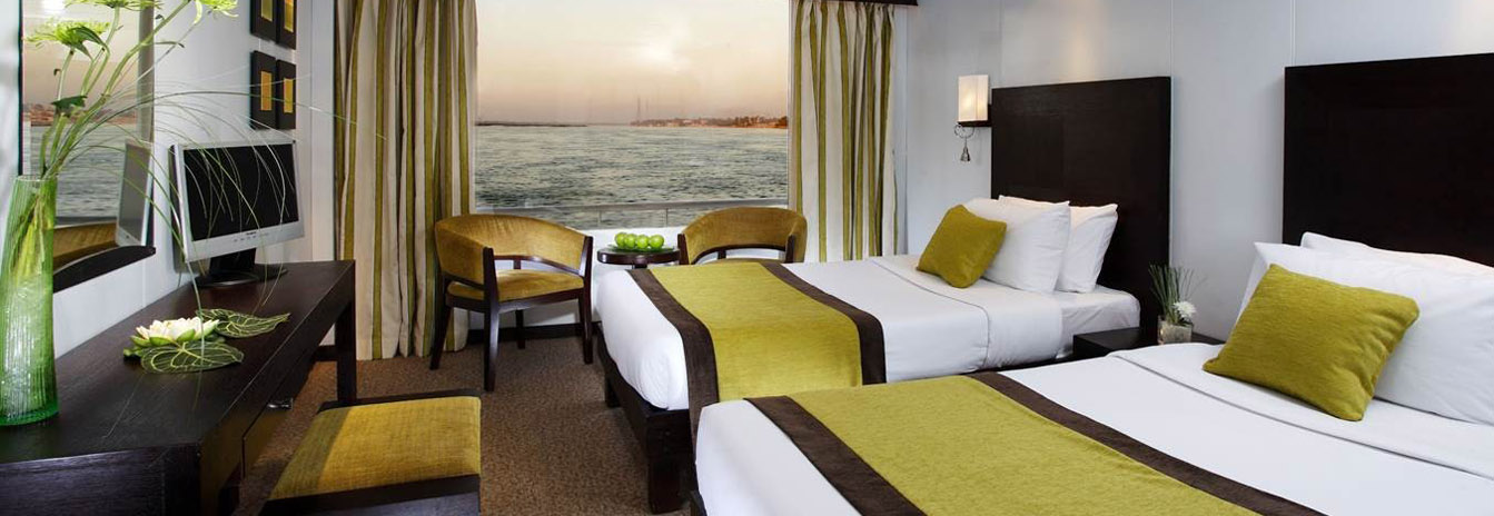 Contemporary luxury cabin on a Mövenpick Nile Cruise with large windows and elegant wood finishes.