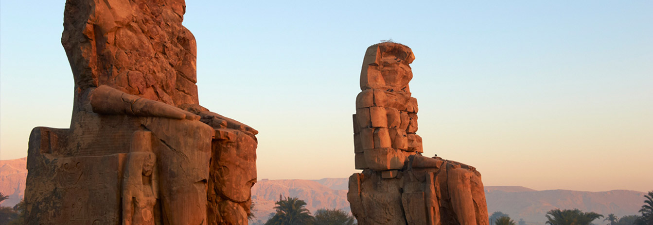 Two massive stone statues of Pharaoh Amenhotep III known as the Colossi of Memnon in Luxor.