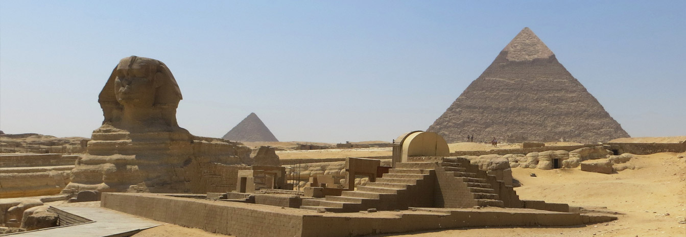 The Great Sphinx of Giza with the pyramids in the background under a clear blue sky.
